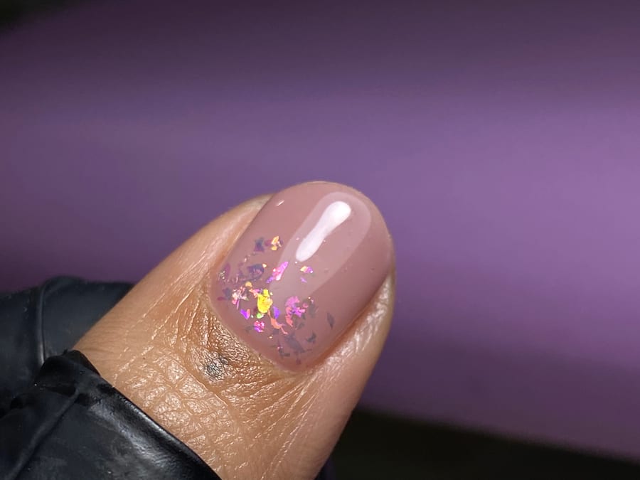 Uña con capping en gel, base nude y escamas holográficas rosadas, hecho en Nails by Mery