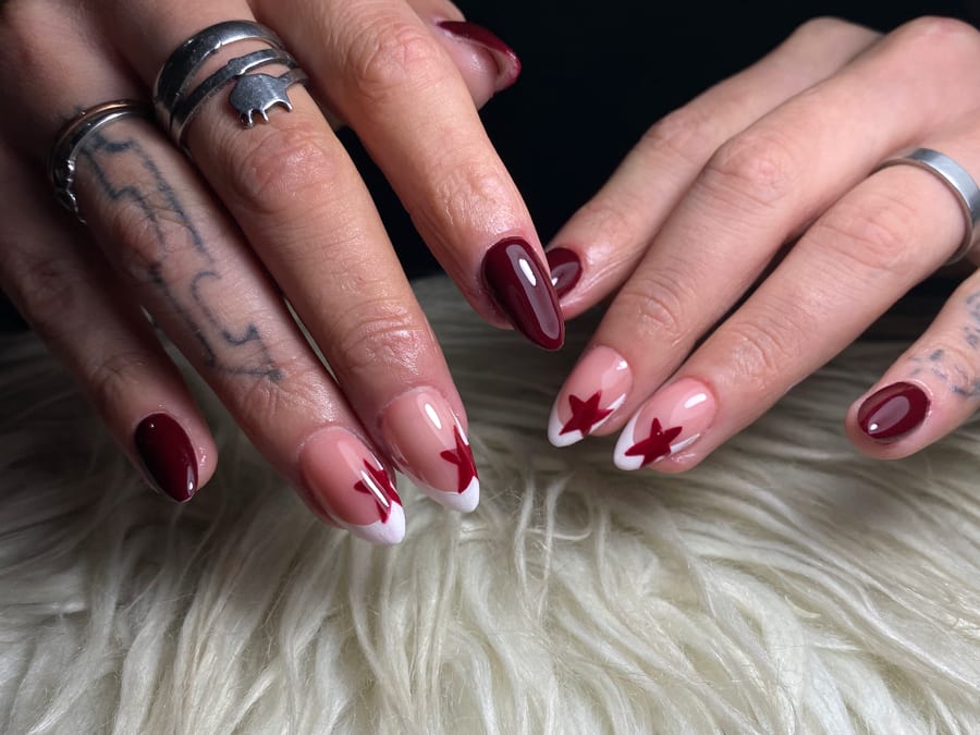 Uñas esculpidas largas en almendra, bordó con francesa blanca y estrellas rojas, hechas en Nails by Mery
